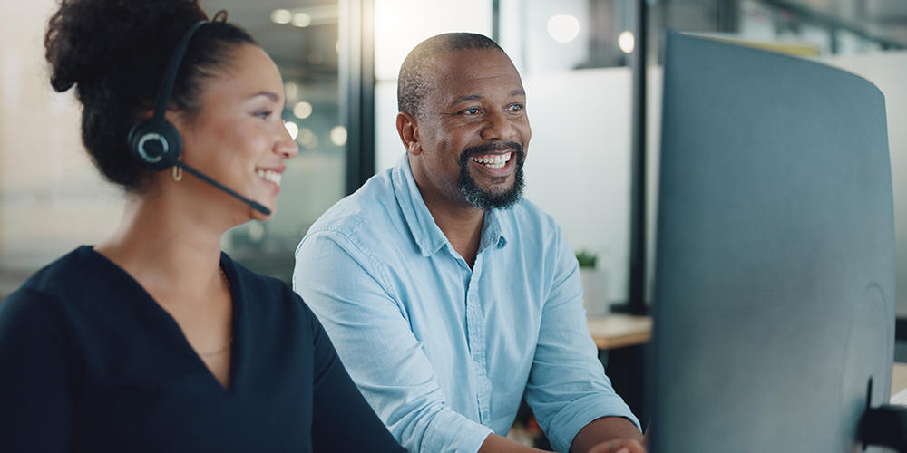 Two people looking at a computer monitor, smiling
